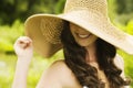 Smiling young woman in sun hat against background of summer green park covering her eyes. Beautiful healthy happy girl Royalty Free Stock Photo