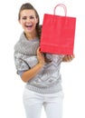 Smiling young woman in sweater showing christmas shopping bag Royalty Free Stock Photo