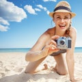 Smiling woman taking photo with retro photo camera on beach Royalty Free Stock Photo