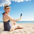 Smiling young woman taking selfie with mobile phone on seashore Royalty Free Stock Photo