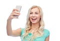 Smiling young woman taking selfie with smartphone Royalty Free Stock Photo