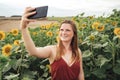 Smiling young woman taking selfie using mobile phone in sunflower field during spring season Royalty Free Stock Photo