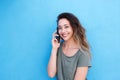 Smiling young woman talking on cellphone against blue wall Royalty Free Stock Photo