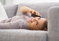 Smiling young woman talking mobile phone while laying on couch Royalty Free Stock Photo