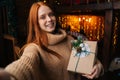 Portrait of smiling young woman thanking boyfriend for box with Christmas present looking at camera.