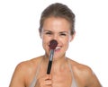 Smiling young woman touching nose with brush
