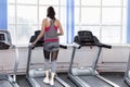 Smiling young woman on a treadmill in the gym. Active lifestyle and health. Back view Royalty Free Stock Photo