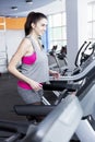 Smiling young woman on a treadmill in the gym. Active lifestyle and health. Vertical Royalty Free Stock Photo