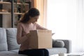 Smiling young woman unpacking cardboard box with internet store order Royalty Free Stock Photo