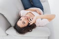 Smiling young woman using cellphone on sofa at home