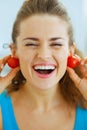 Smiling young woman using cherry tomato as earrings Royalty Free Stock Photo