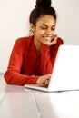 Smiling young woman using laptop while lying on floor Royalty Free Stock Photo