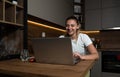 Smiling young woman using laptop, sitting on chair at home, beautiful girl shopping or chatting online in social network, having f Royalty Free Stock Photo