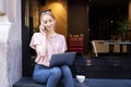 Smiling young woman using mobile phone and laptop while sitting in the cafe Royalty Free Stock Photo