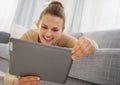 Smiling young woman using tablet pc while laying on sofa Royalty Free Stock Photo