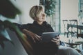 Smiling young woman wearing casual clothes and using electronic device while spending relax time home livingroom