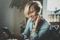 Smiling young woman wearing casual clothes and using electronic device while spending relax time home livingroom