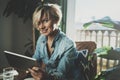 Smiling young woman wearing casual clothes and using electronic device while spending relax time home livingroom