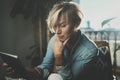 Smiling young woman wearing casual clothes and using electronic device while spending relax time home livingroom