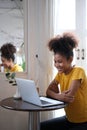 Smiling young woman wearing casual clothes working remotely, surfing internet on laptop while sitting in cafe Royalty Free Stock Photo