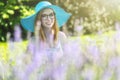 Smiling young woman wearing turquoise summer hat is posing in the garden