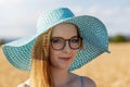 Smiling young woman wearing turquoise summer hat is posing in the sunny day