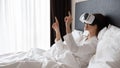 Smiling young woman wearing virtual reality glasses, testing device in bed. Royalty Free Stock Photo