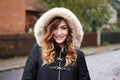 Smiling young woman wearing winter coat with fake fur hood Royalty Free Stock Photo