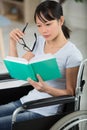 smiling young woman in wheelchair reading book Royalty Free Stock Photo