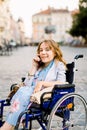 Smiling young woman in wheelchair talking on the phone, working, online consultations, reccomendations online. Young Royalty Free Stock Photo