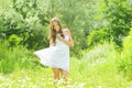Smiling young woman in white dress with flower against background of summer green park. Royalty Free Stock Photo
