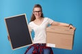 Smiling woman with cardboard box showing blank board on blue Royalty Free Stock Photo
