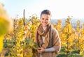 Smiling young woman winegrower standing in autumn grape field