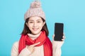 Smiling young woman in winter dress and showing  smart phone Royalty Free Stock Photo