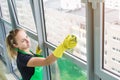 Smiling young woman worker cleaning soap suds on glass window with squeegee and rag Royalty Free Stock Photo