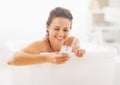 Smiling young woman writing sms in bathtub Royalty Free Stock Photo