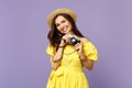 Smiling young woman in yellow dress, summer hat taking pictures on retro vintage photo camera isolated on pastel violet Royalty Free Stock Photo