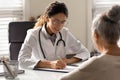 Female doctor write prescription to elderly patient