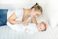 Portrait of smiling young woman lying on bed and looking at her baby son Royalty Free Stock Photo