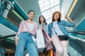 Smiling young women with shopping bags on escalator in shopping mall, young girls shopping concept Royalty Free Stock Photo