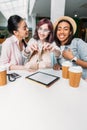 Smiling young women sitting at table with paper cups and showing new stylish shoes Royalty Free Stock Photo