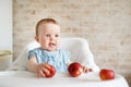 Baby eating fruit. Little girl biting yellow apple sitting in white high chair in sunny kitchen. Healthy nutrition for kids. Solid Royalty Free Stock Photo