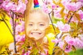 Smilling blonde kid standing in a blooming garden. Blooming cherry. Portrait of beautiful little girl. Close up of Royalty Free Stock Photo