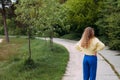 A smilling girl with blond curly hair stands on a path in a picturesque park