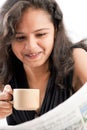 Smilling indian teen reading newspaper with coffee