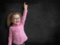 Happy kid inventor with rised hand finding idea near school black chalkboard