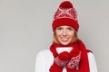 Smilling winter girl in knitted warm hat and mittens holding a cup in hands. Happy christmas woman, isolated on gray background Royalty Free Stock Photo