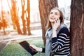 Smilling young woman with digital tablet in hand talking on mobile phone with boyfriend before a meeting with it Royalty Free Stock Photo