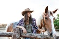 Smilng woman cowgirl standing with her horse on ranch Royalty Free Stock Photo
