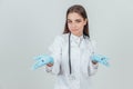 Smilng young female doctor showing to the camera open palms with syringes.